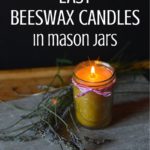 A glowing beeswax candle in a mason jar rests on a gray surface, tied with pink and white string. Dried lavender stems accompany it, exuding rustic elegance. Text above reads "Easy Beeswax Candles in Mason Jars," showcasing Rootsy's signature charm.