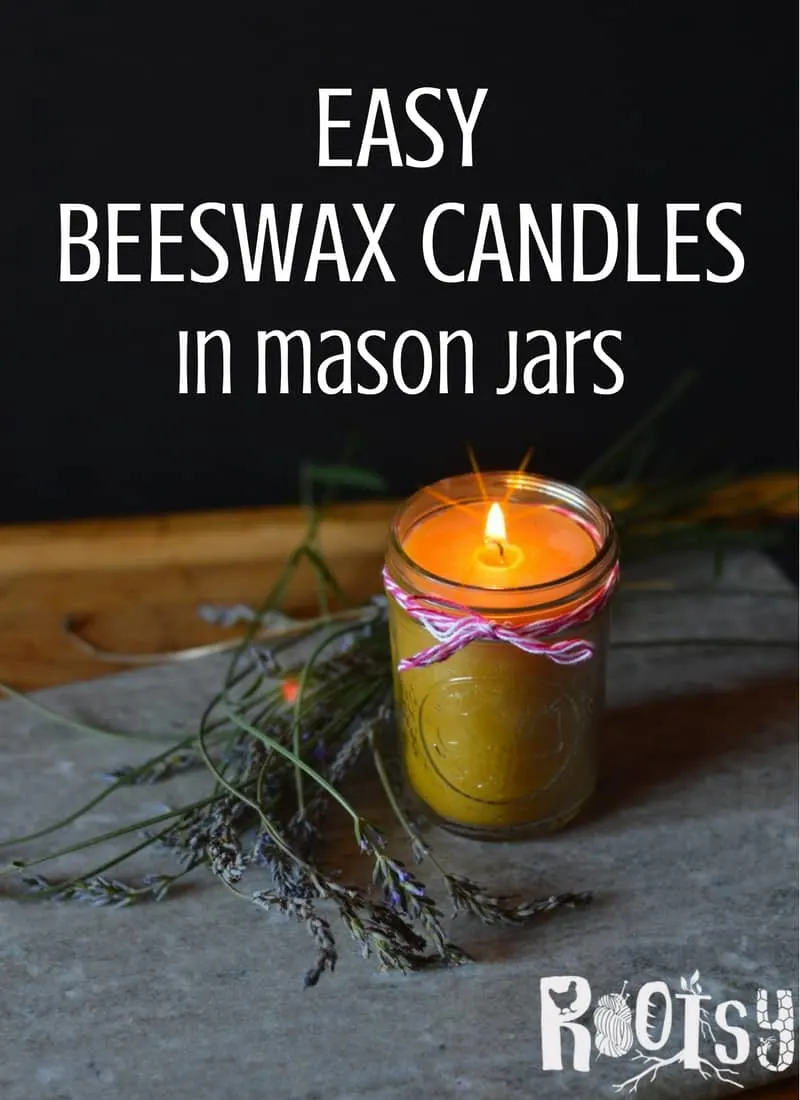 A lit beeswax candle in a mason jar sitting on a rock surrounded by sprigs of lavender with text overlay