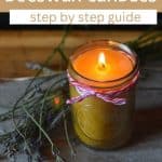 A lit beeswax candle in a jar, tied with pink and white string, sits on a surface next to sprigs of lavender. Text above reads, "How to make beeswax candles: step by step guide. Rootsy.org." Perfect for DIY beeswax candles lovers.