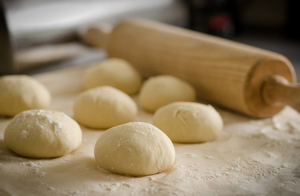 Image of bread dough on floured surface with rolling pin