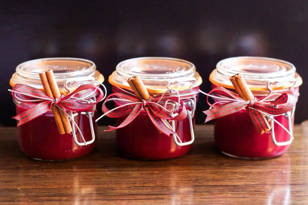 image of three candles in canning jars with ribbon and cinnamon sticks
