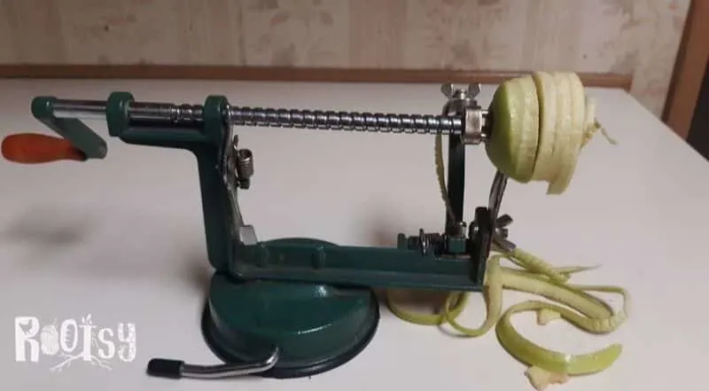 An apple being peeled and cored on a rotary peeling machine.