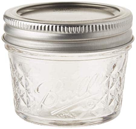 A small, clear glass jar with a metal lid, featuring a quilted pattern and the word "Ball" embossed on its side—perfect for creating unique gifts in a jar.