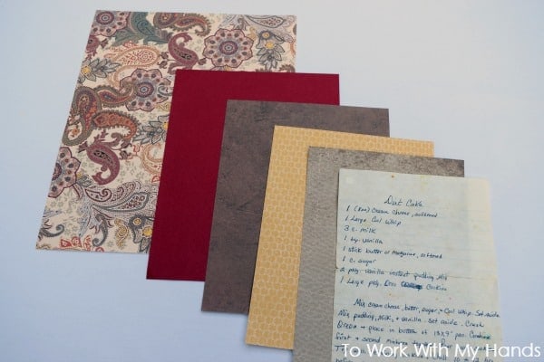 A variety of decorative papers in a fan layout, including a paisley pattern, solid red, and textured browns and yellows. Beside them, a handwritten recipe is laid out on a lined page.