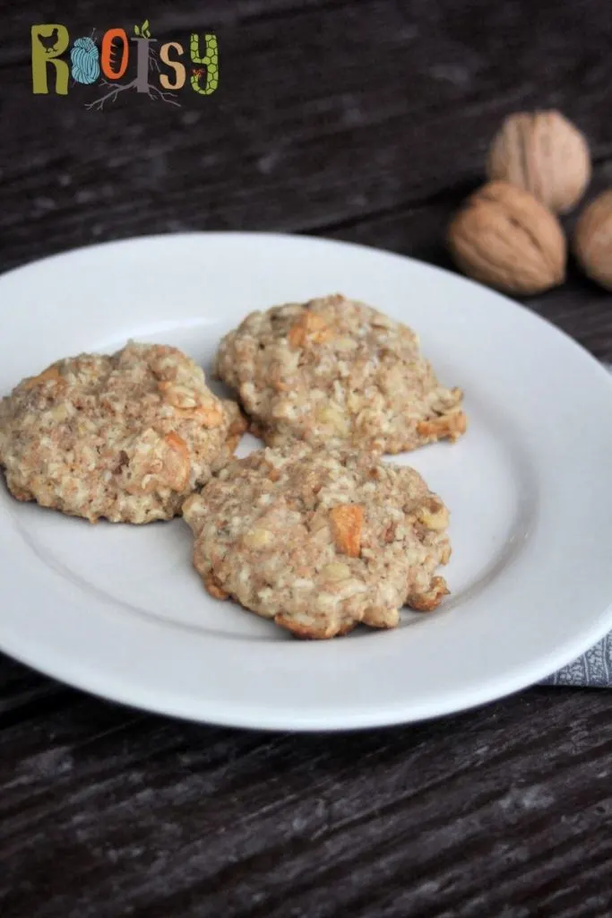 Apple oatmeal cookies on a plate with walnuts in shell behind it. 