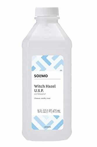 A clear plastic bottle of Solimo Witch Hazel U.S.P. Astringent, 16 fl oz (473 ml), perfect for cleansing and soothing skin after using your favorite bath bombs. The label features a blue geometric pattern, ensuring a refreshing touch to your self-care routine.