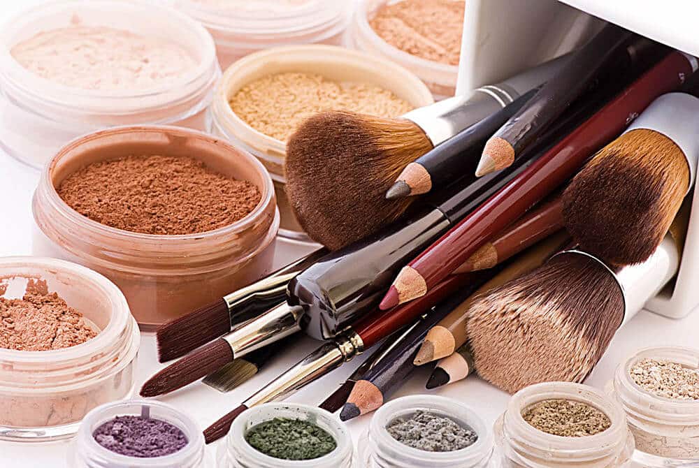 A money-saving collection of makeup items featuring jars of loose powder in shades from light to dark, several versatile brushes for every application, and eyeliner pencils—all perfect bathroom essentials for your beauty routine.