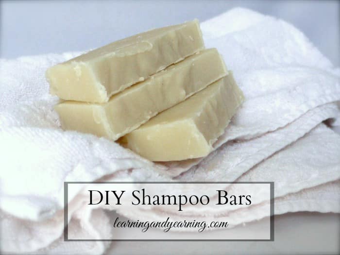 Three homemade soap bars are stacked on white towels in a cozy bathroom setting. Text overlay reads "DIY Shampoo Bars," highlighting a perfect money-saving solution, followed by a website URL.