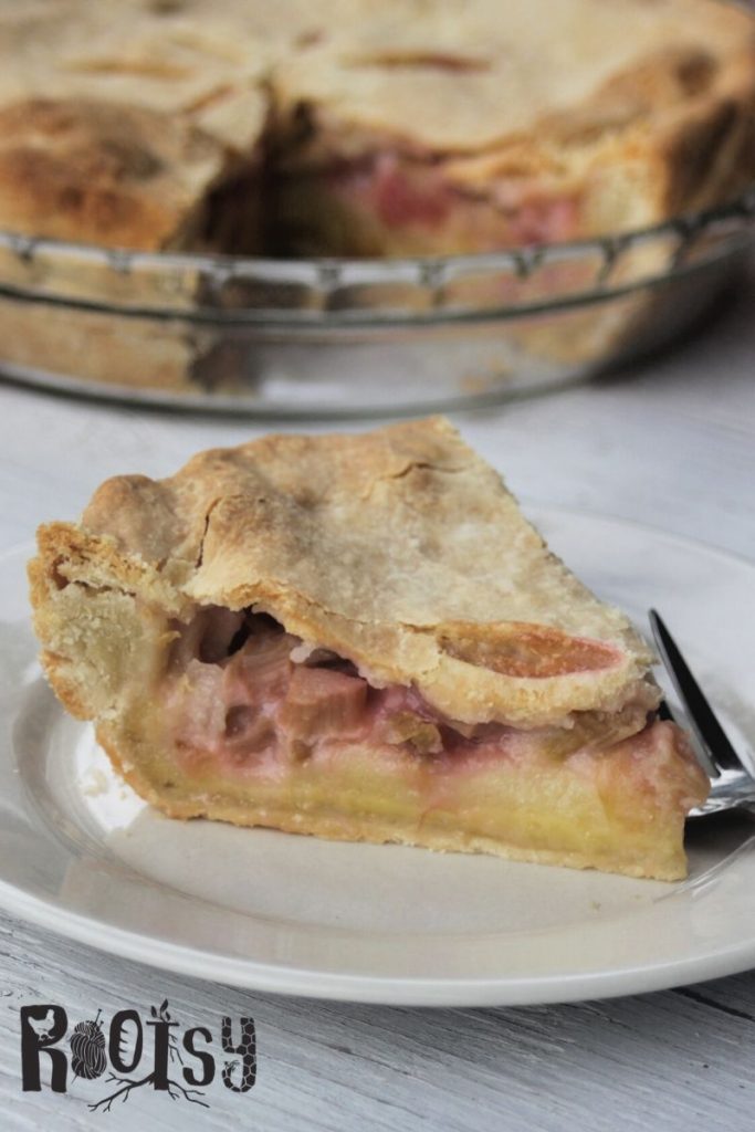 A slice of rhubarb custard pie on a white plate with a fork. 