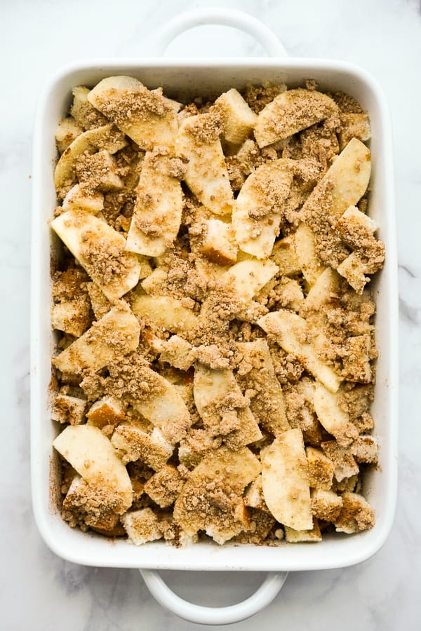 A white baking dish brimming with sliced apples and a crumbly mixture of brown sugar and spices, this tempting treat is a must-try from the collection of classic apple recipes, ready to be baked.