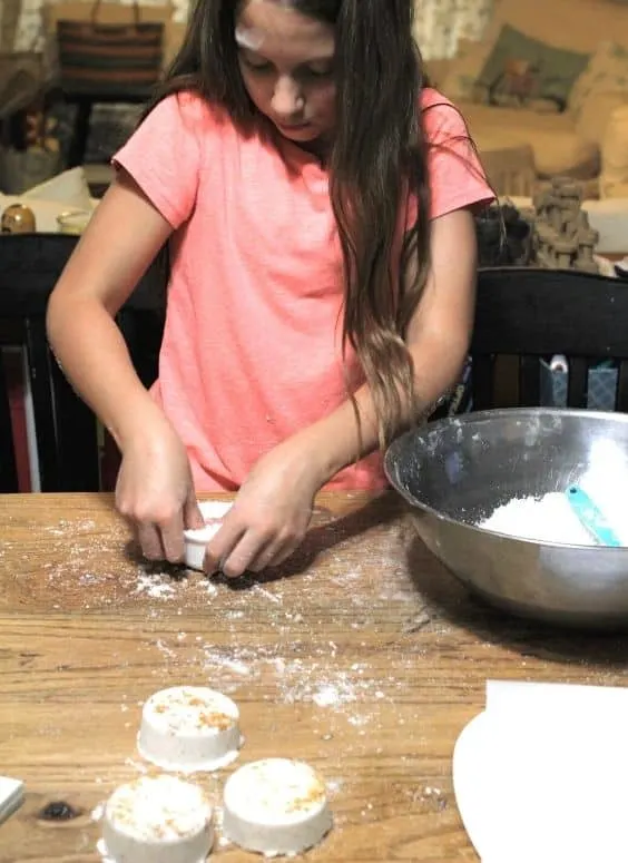 child making bath bombs by pressing the bath bomb recipe into a mold