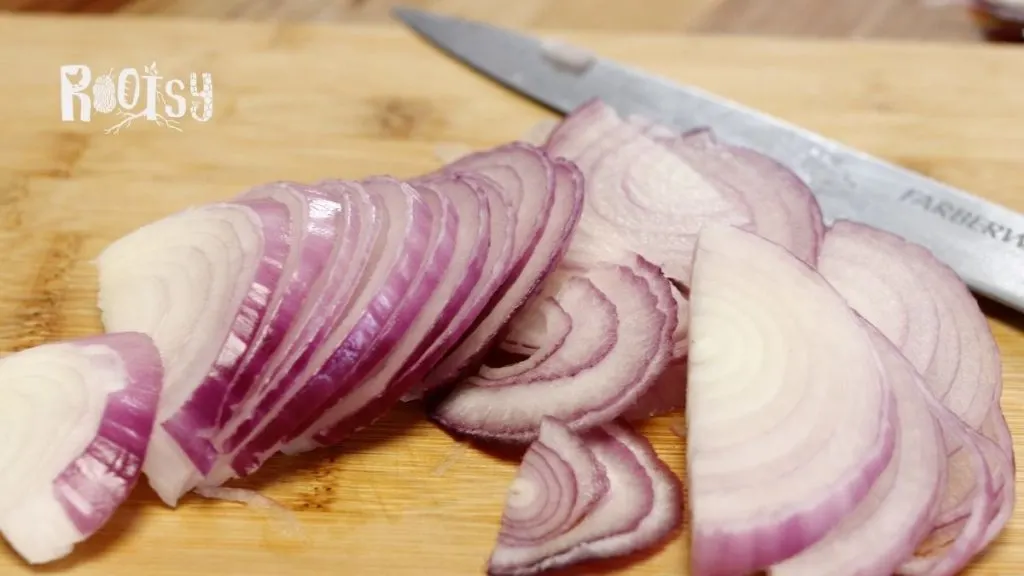 red onion slices on wooden cutting board with knife