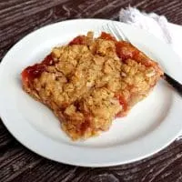 A rhubarb oatmeal bar on a plate with a fork.