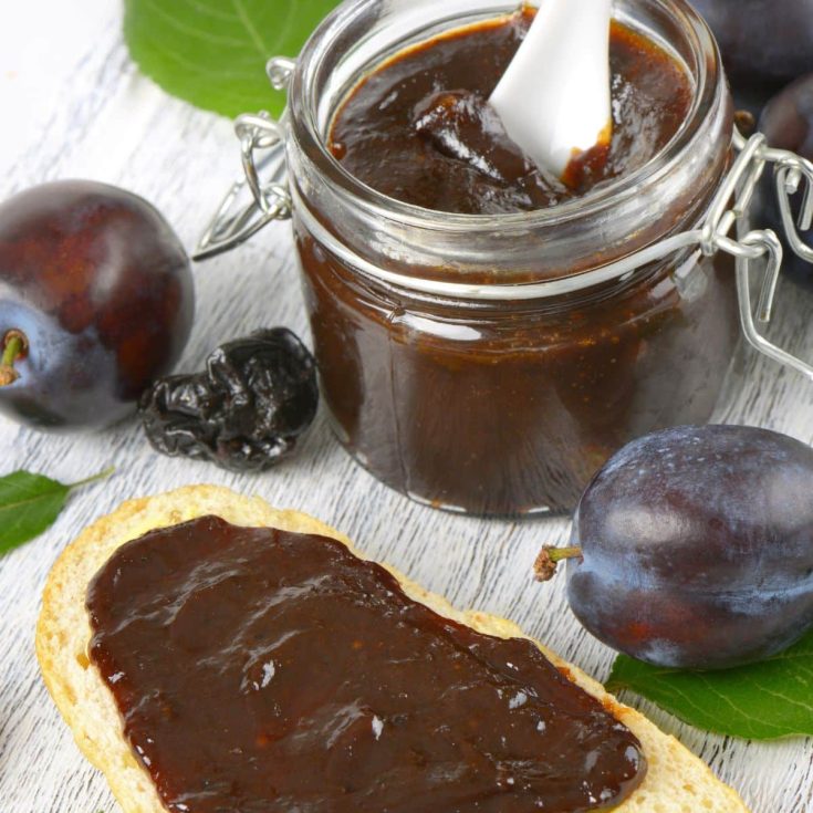 home canned plum butter on toast with plums and a jar of plum butter in background