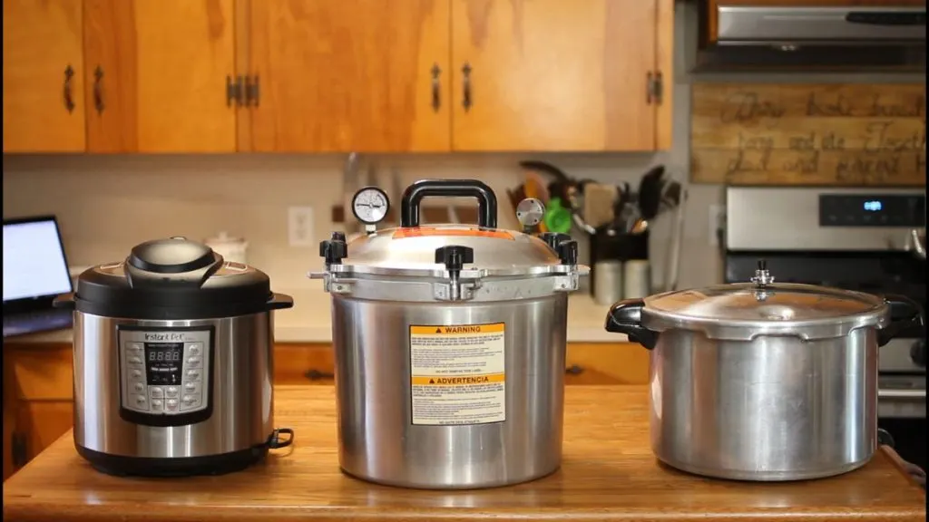 3 different pressure canners sitting on a kitchen countertop.