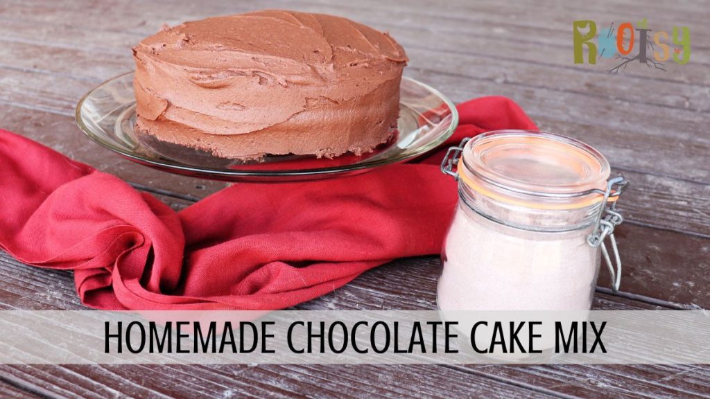 A frosted chocolate cake sits on a glass cake plate with a red cloth surrounding it. A jar of cake mix sits to the right. Text overlay reads: homemade chocolate cake mix. 