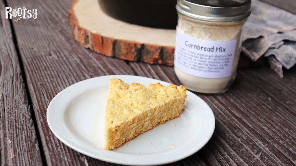 A slice of cornbread sits on a white plate with a jar of cornbread mix in the background.