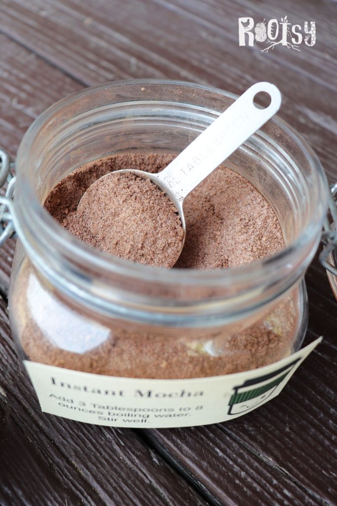 An open jar with brown powder inside sits with a spoon sticking out of the top.