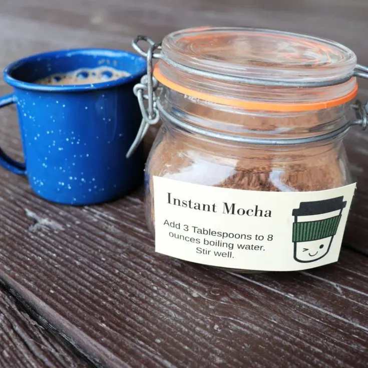 A jar labeled instant mocha sits next to a blue tin coffee mug.