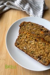 two slices of zucchini carrot bread with applesauce on a white plate.